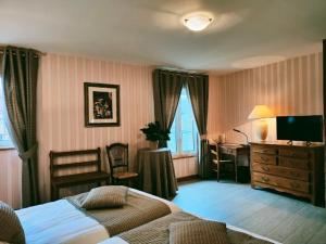 ein Schlafzimmer mit einem Bett, einem Schreibtisch und einem Fernseher in der Unterkunft La Chaumière in Aubigny-sur-Nère