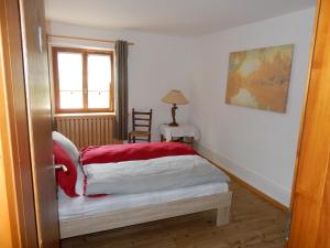 a bedroom with a bed with a red and white blanket at Au Cheval Blanc in Asuel