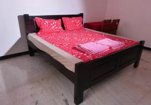 a bed with red sheets and red pillows on it at Villa Souhayl homestay in Puducherry