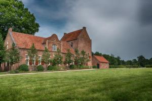 un grande edificio in mattoni con un grande campo erboso di Ferienwohnung Zur Mühle a Weener