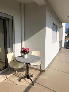 une table avec deux chaises et un vase de fleurs sur le balcon dans l'établissement Erik Apartment, à Nazaré