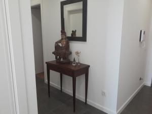 une statue sur une table dans un couloir avec un miroir dans l'établissement Erik Apartment, à Nazaré