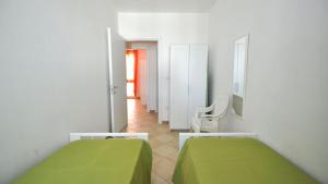 a bedroom with two green beds and a hallway at Villetta Bianca by Salento Affitti in Torre San Giovanni Ugento
