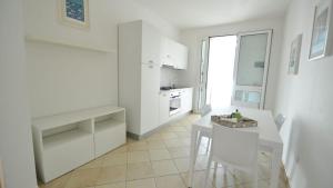 a white kitchen with a white table and a table and chairs at Villetta Bianca by Salento Affitti in Torre San Giovanni Ugento