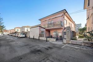 a street with cars parked in front of a pink building at Victoria Apartments Fil Rouge in Diano Marina