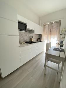 a white kitchen with white cabinets and a table at Chez Telly 31 in Verona