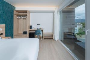 a bedroom with a desk and a window and a table at Hotel Spa Meiga do Mar in Caldebarcos