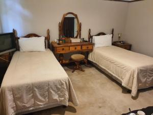 a bedroom with two beds and a vanity and a mirror at Lord Fraser Guest House in Wepener