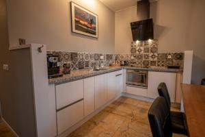 a kitchen with white cabinets and a table and a microwave at Brinkzicht Diever, appartement Bert in Diever