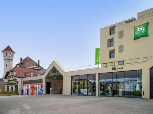 un magasin devant un bâtiment avec une tour d'horloge dans l'établissement ibis Styles Paris Romainville, à Romainville