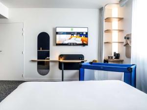 1 dormitorio con 1 cama y TV en la pared en ibis Styles Paris Romainville, en Romainville