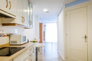 cocina con armarios blancos y microondas blanco en Apartamentos Turísticos Alba, en Cartagena