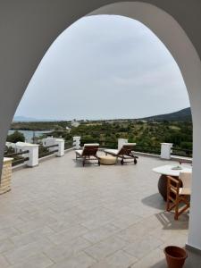 un arco sobre un patio con mesas y sillas en The Beach House Μουτσούνα Νάξος, en Moutsoúna