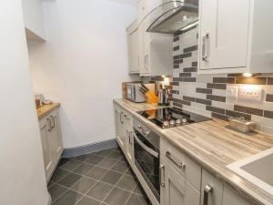 uma cozinha com armários brancos e uma bancada em The Flat em Barnard Castle