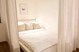 małe łóżko z białą pościelą i poduszkami w obiekcie Modernes Apartment, Stadtnah, Stellplatz, nähe Mosel w Koblencji