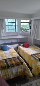 two beds in a room with two windows at Sitio-Estalagem Purioca in Cunha