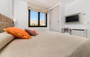 una camera da letto con un letto con cuscini arancioni e una TV di Hoposa Niu a Cala Sant Vicenç