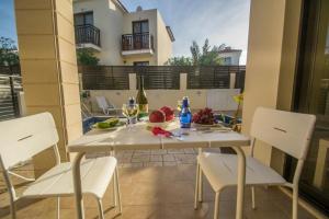 een witte tafel met witte stoelen en wijnglazen erop bij Protaras Allium Villa in Protaras