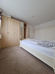 a bedroom with a large white bed and cabinets at Croydon - Compton in South Norwood