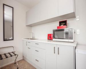 a kitchen with white cabinets and a microwave at Colombo Lodge Hotel in Christchurch