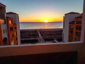 uma vista para o pôr-do-sol a partir da varanda de um edifício em Agréable appart rénové vue mer 4 pers Parking Wifi em Le Barcarès