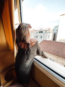 Eine Frau in einem Kleid, die aus dem Fenster schaut. in der Unterkunft La mouette ermou street, Athens in Athen