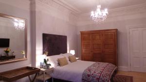 1 dormitorio con cama, espejo y lámpara de araña en Antler Guest House, en Edimburgo