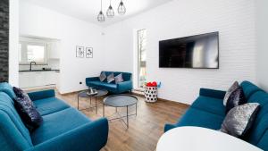 a living room with blue couches and a tv at Apartamenty Sun & Snow Dom Sarnia 37 in Karpacz