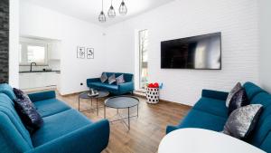 a living room with blue couches and a tv at Dom Sarnia 37, Sun & Snow in Karpacz