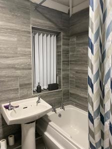 a bathroom with a sink and a bath tub at Cosy 3 Bedroom house, Free parking & WIFI in Nottingham