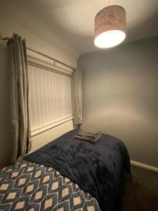 um quarto com uma cama e um candeeiro com toalhas em Cosy 3 Bedroom house, Free parking & WIFI em Nottingham