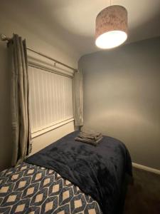 a bedroom with a bed and a lamp with towels on it at Cosy 3 Bedroom house, Free parking & WIFI in Nottingham