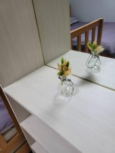 dos jarrones con flores en ellos sentados en una mesa en House that only walks on flowery paths, en Wonju