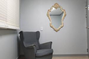 a chair and a mirror on a wall at House that only walks on flowery paths in Wonju