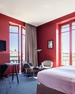 a hotel room with red walls and a bed and chairs at Villa Mirasol in Mont-de-Marsan