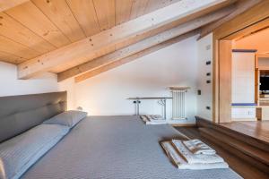 1 dormitorio con cama grande y techo de madera en La Pratolina Attico, en Castello di Fiemme