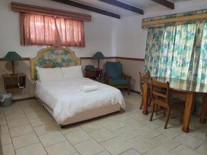Un dormitorio con una cama y una mesa y sillas. en Lord Fraser Guest House, en Wepener