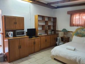 1 dormitorio con 1 cama, armarios de madera y TV en Lord Fraser Guest House, en Wepener
