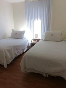 2 camas en una habitación blanca con ventana en RoomApart Escuela Militar, en Santiago