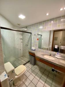 a bathroom with a toilet and a sink and a mirror at Aconchego com vista mar in Vila Velha