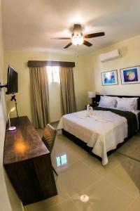 a bedroom with a bed and a desk and a ceiling fan at Halibut Hotel in La Romana