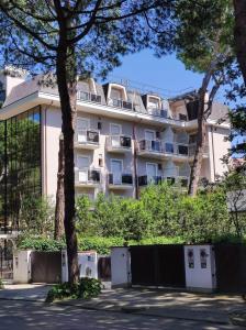 duży biały budynek z drzewami przed nim w obiekcie Hotel Arlecchino w mieście Milano Marittima