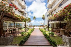 a walkway between two buildings with tables and flowers at PÉ NA AREIA - 2 qt - 2 WC - PISCINA - wifi - garagem privativa in João Pessoa