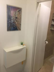 a bathroom with a white cabinet and a painting on the wall at REoN Apartment No 8, Osijek - self CHECK IN in Osijek