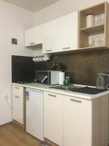 cocina con armarios blancos y microondas en REoN Apartment No 8, Osijek - self CHECK IN en Osijek