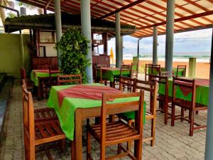 ヒッカドゥワにあるSerenade Beach Hotelの緑のテーブルと椅子が備わるレストラン、ビーチを提供しています。