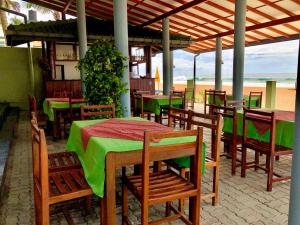 a restaurant with green tables and chairs and the beach at Serenade Beach Hotel in Hikkaduwa