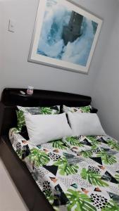 Cama con edredón y almohadas de color negro y verde en Casa Erelle -1 Bedroom guest house w/ modern kubo en Antipolo