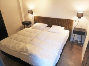 a bed with white sheets and pillows in a bedroom at DBO81 Spacious apartment in the center and beach nearby in Domburg