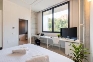 a bedroom with a large window and a desk with a tv at Camplus San Pietro in Rome